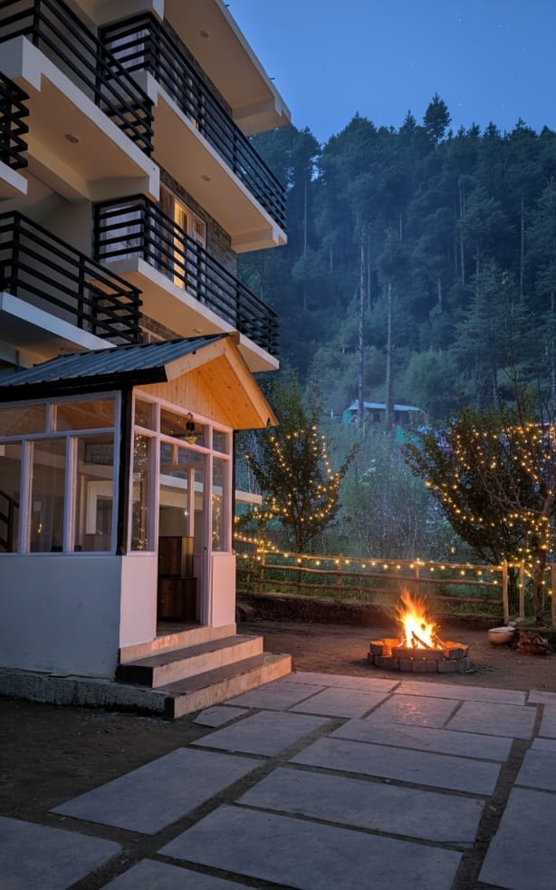 Hils&Paws homestay property with cozy outdoor fireplace at dusk in Old Manali